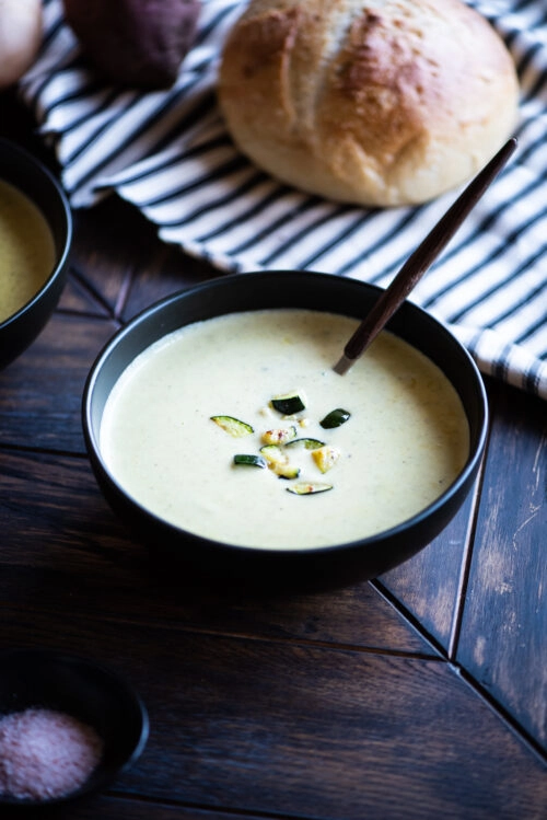 zucchini and sweet potato soup served with a spoon