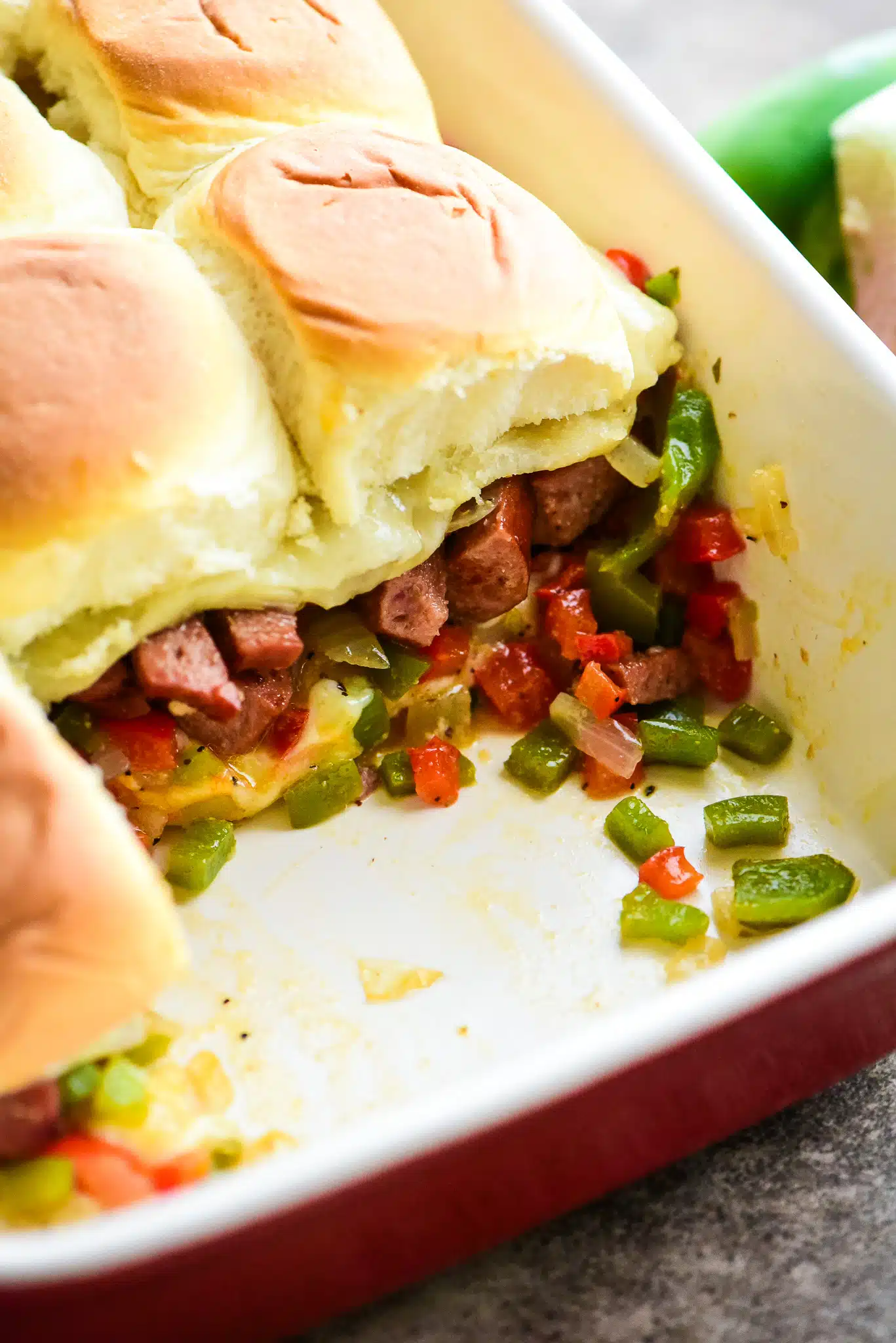 sausage & peppers sliders in a casserole dish