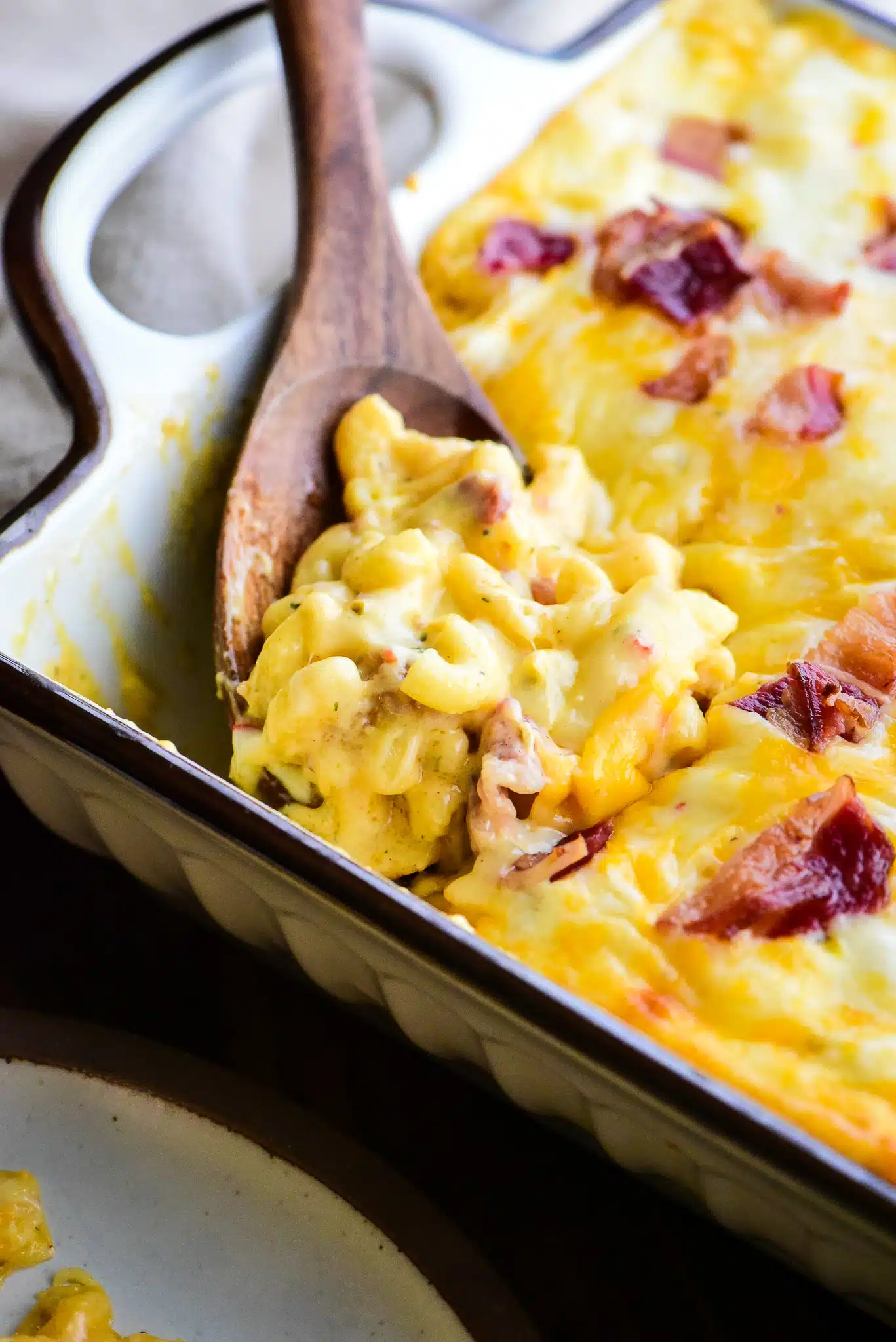 using a spoon to serve the beef bacon mac and cheese